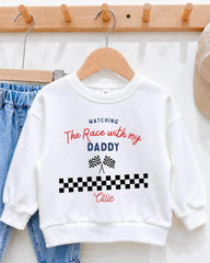 A white sweatshirt with a personalized message printed on it, hanging on a wooden hanger.