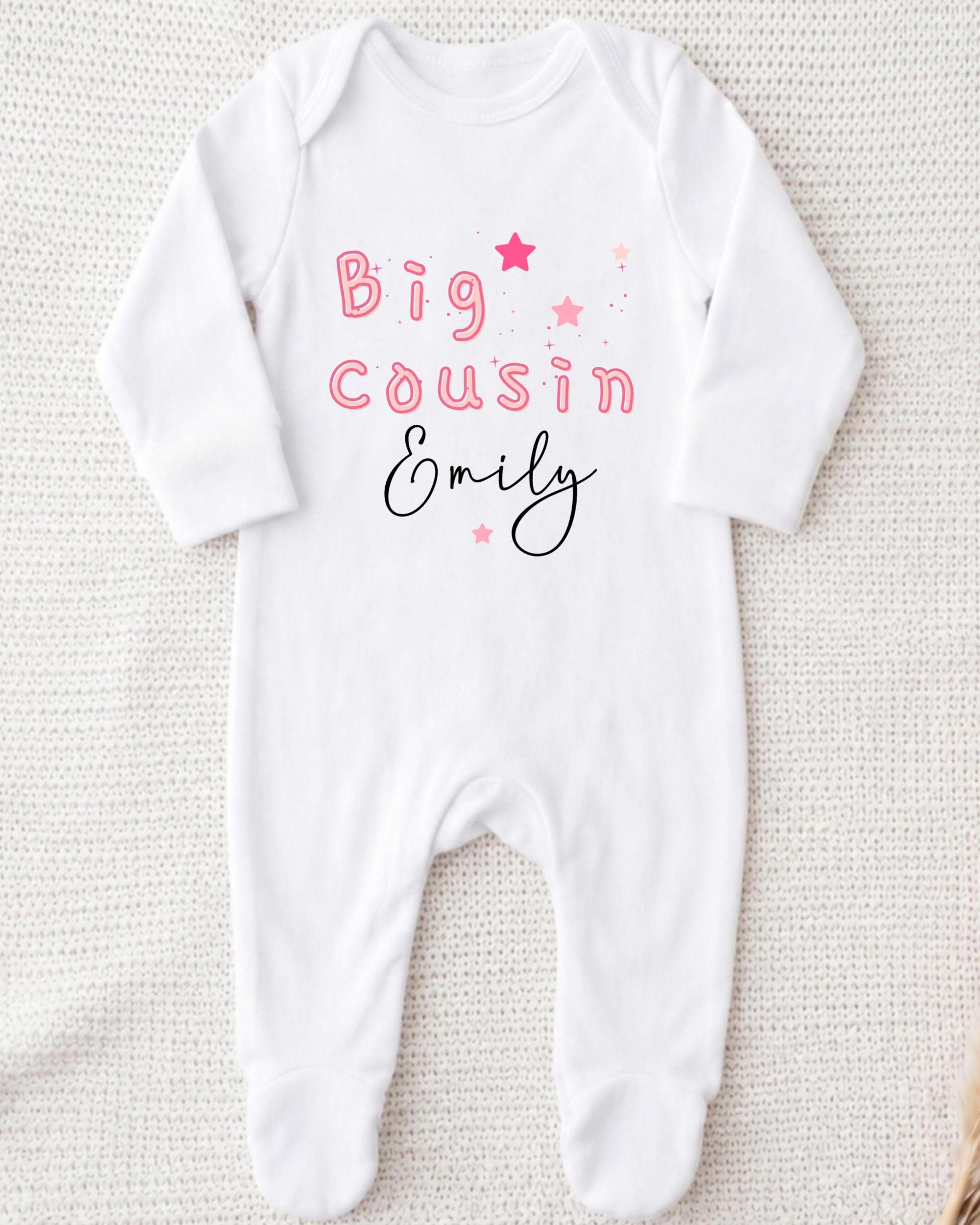 A white onesie with the text "Big Cousin Emily" printed on it.