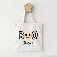 A white tote bag with the text "BOO Oscar" printed on it, along with a skull and ghost design.