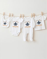 A collection of baby clothes, including onesies and bibs, hanging on a clothesline.