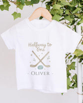 A white t-shirt with a graphic design and text printed on it, hanging on a wooden hanger.