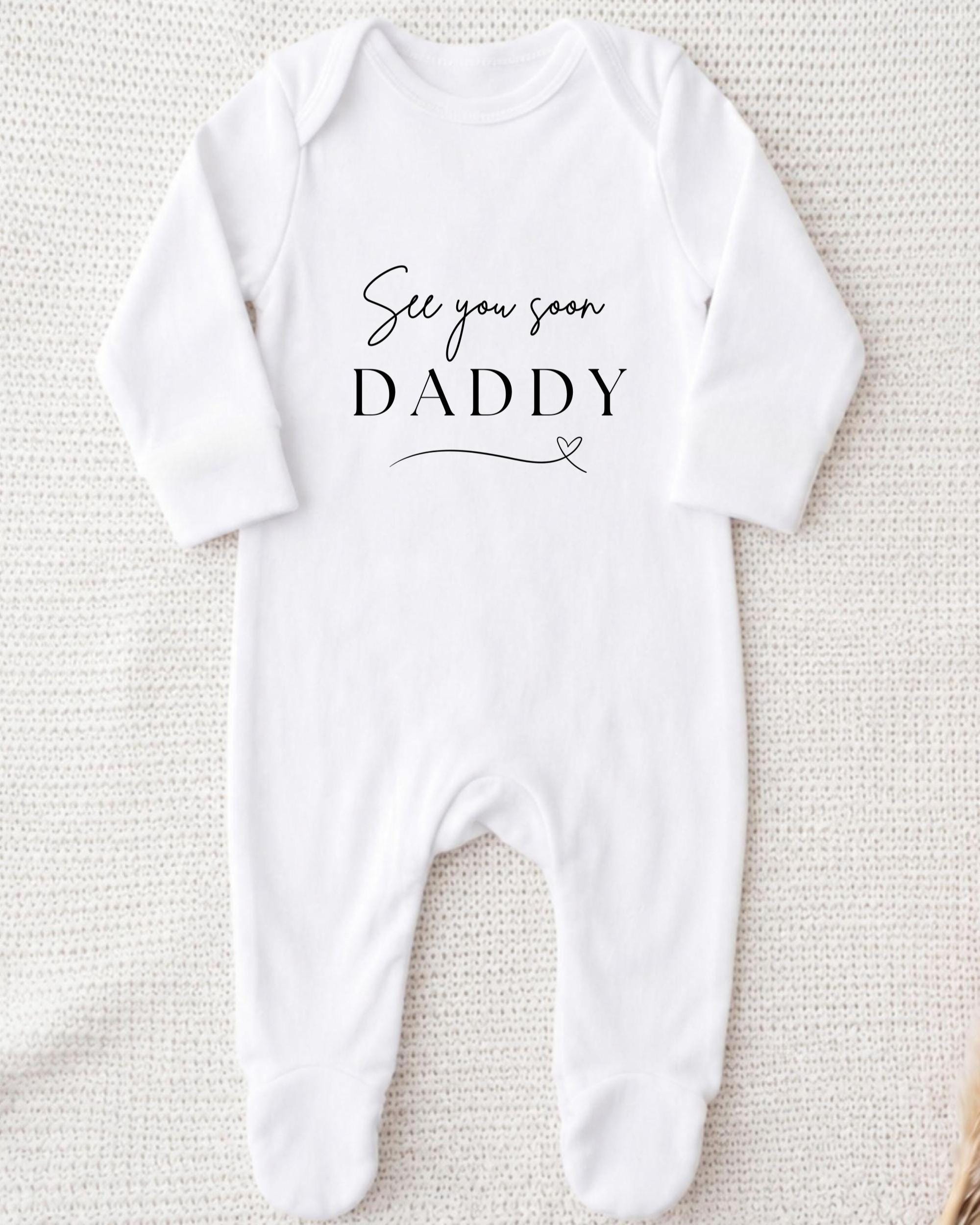 A white onesie with the text "See you soon Daddy" printed on it.