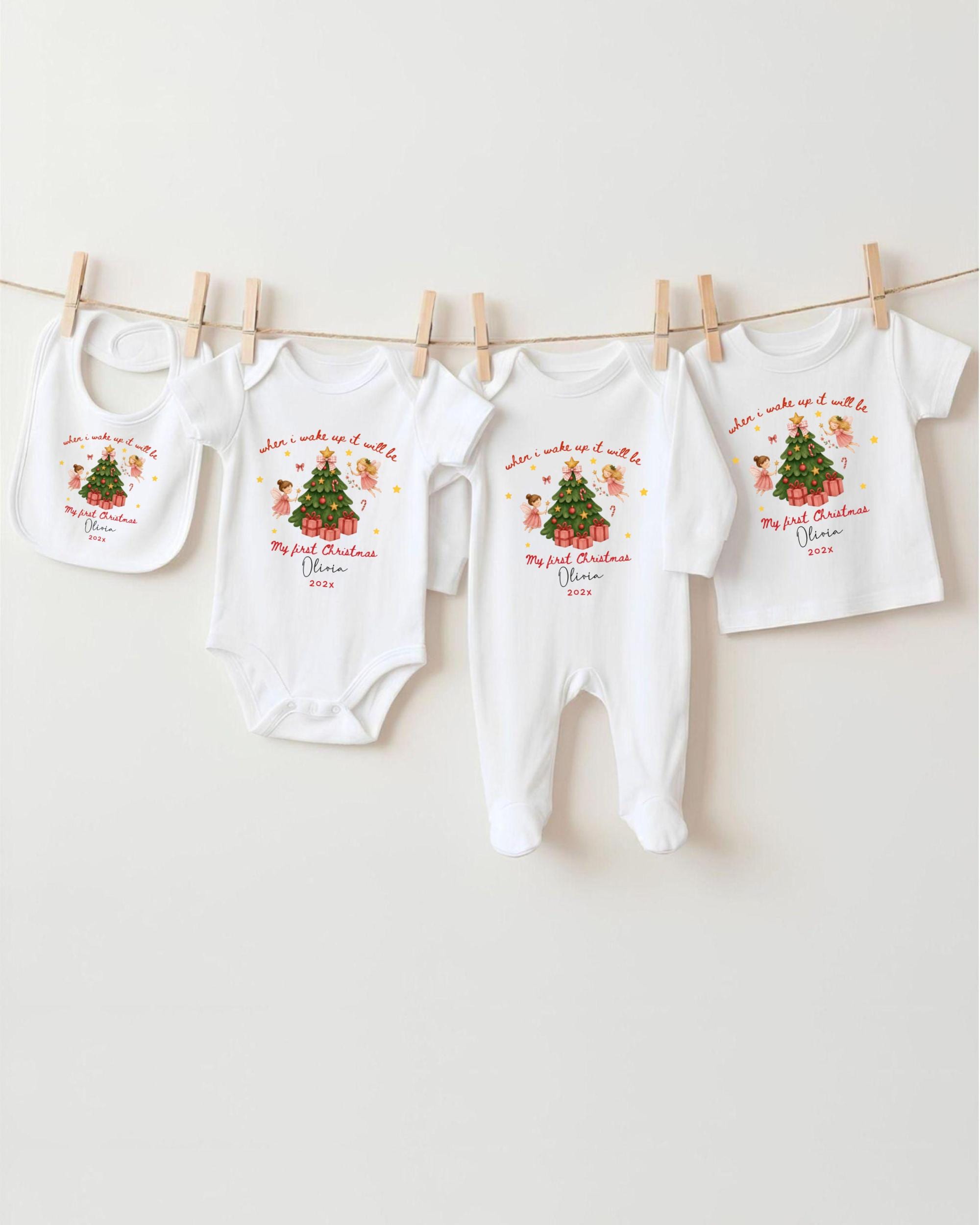 A row of white baby clothes with Christmas-themed designs hanging on a clothesline.