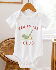 A white baby onesie with the text "NEW TO THE CLUB" printed on it, along with a golf club graphic.