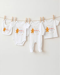 A row of white baby clothes with gingerbread man designs hanging on a clothesline.
