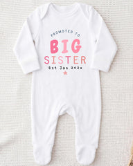 A white onesie with text that reads "Promoted to BIG SISTER Est Jan 2023*" printed on it.