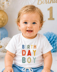 A smiling baby boy wearing a white t-shirt with the text "BIRTHDAY BOY" printed on it.