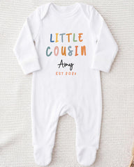A white onesie with the text "LITTLE COUSIN Amy EST 202x" printed on it.