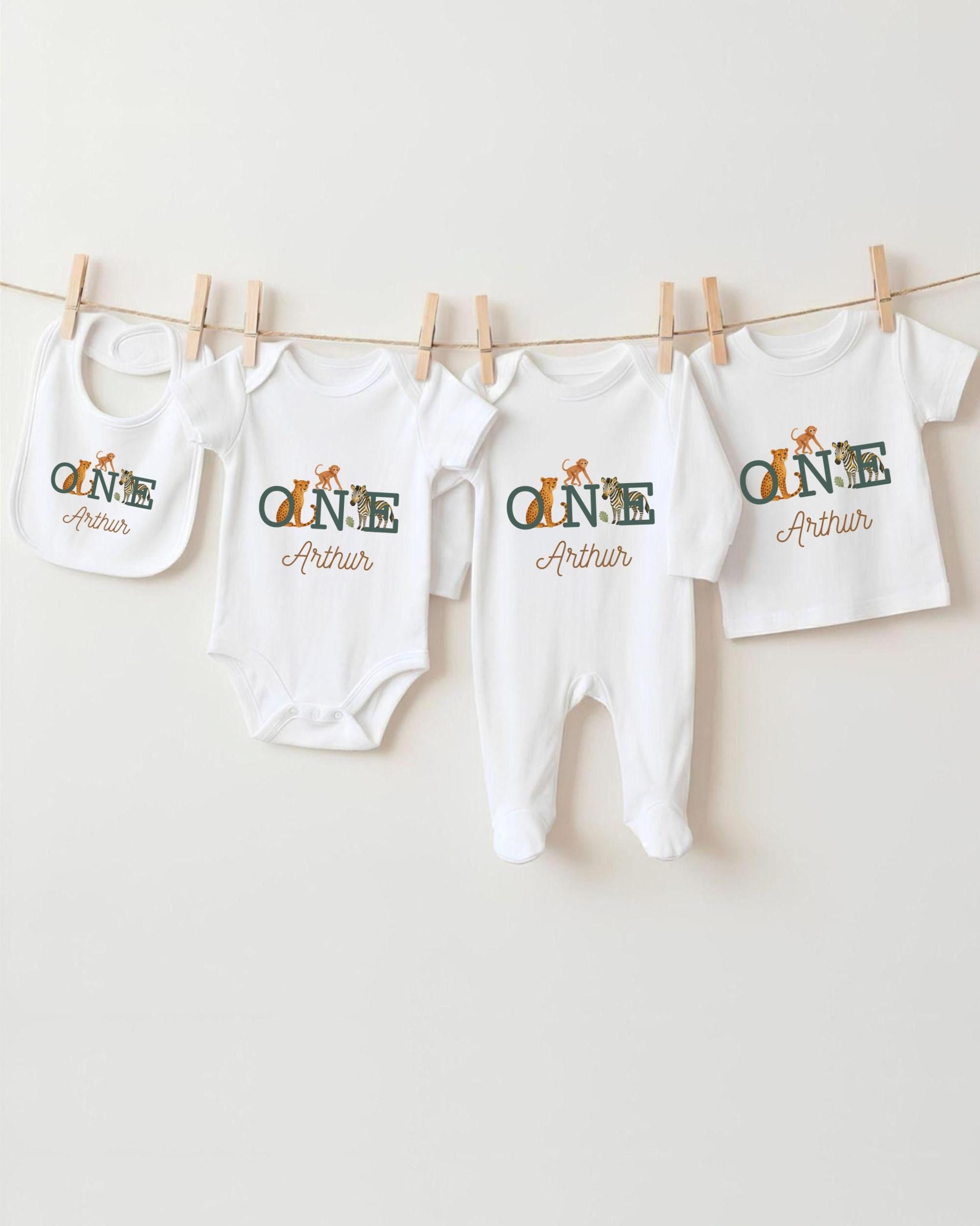 A collection of baby clothes, including onesies and bibs, hanging on a clothesline.
