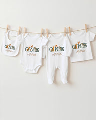 A collection of baby clothes, including onesies and bibs, hanging on a clothesline.