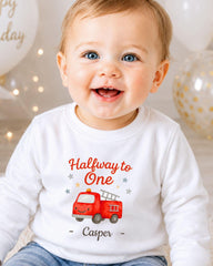 A smiling baby boy wearing a white shirt with a red fire truck graphic and the text "Halfway to One - Casper" printed on it.