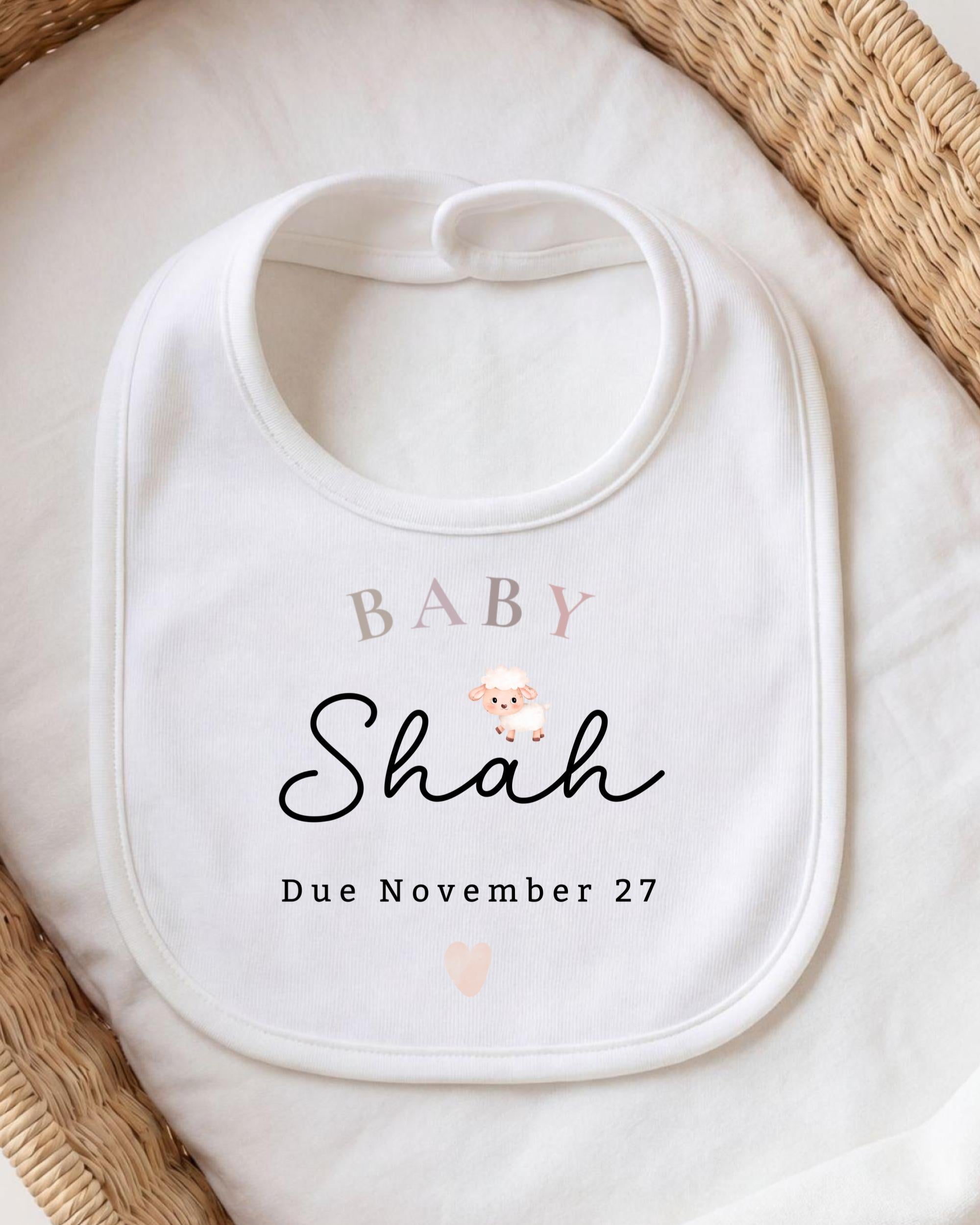 A white baby bib with personalized text and a small sheep illustration.