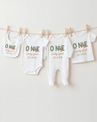 A row of white baby clothes with the name "OLIVER" printed on them, hanging on a clothesline.