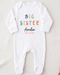 A white onesie with the text "BIG SISTER Amelia EST 202x" printed on it.