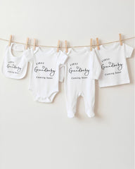 A row of four white baby clothes hanging on a clothesline, each with a different size printed on it.