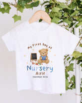 A white t-shirt with a teddy bear and a chalkboard, along with the text "My First Day of Nursery Aifie" and "September 2023".