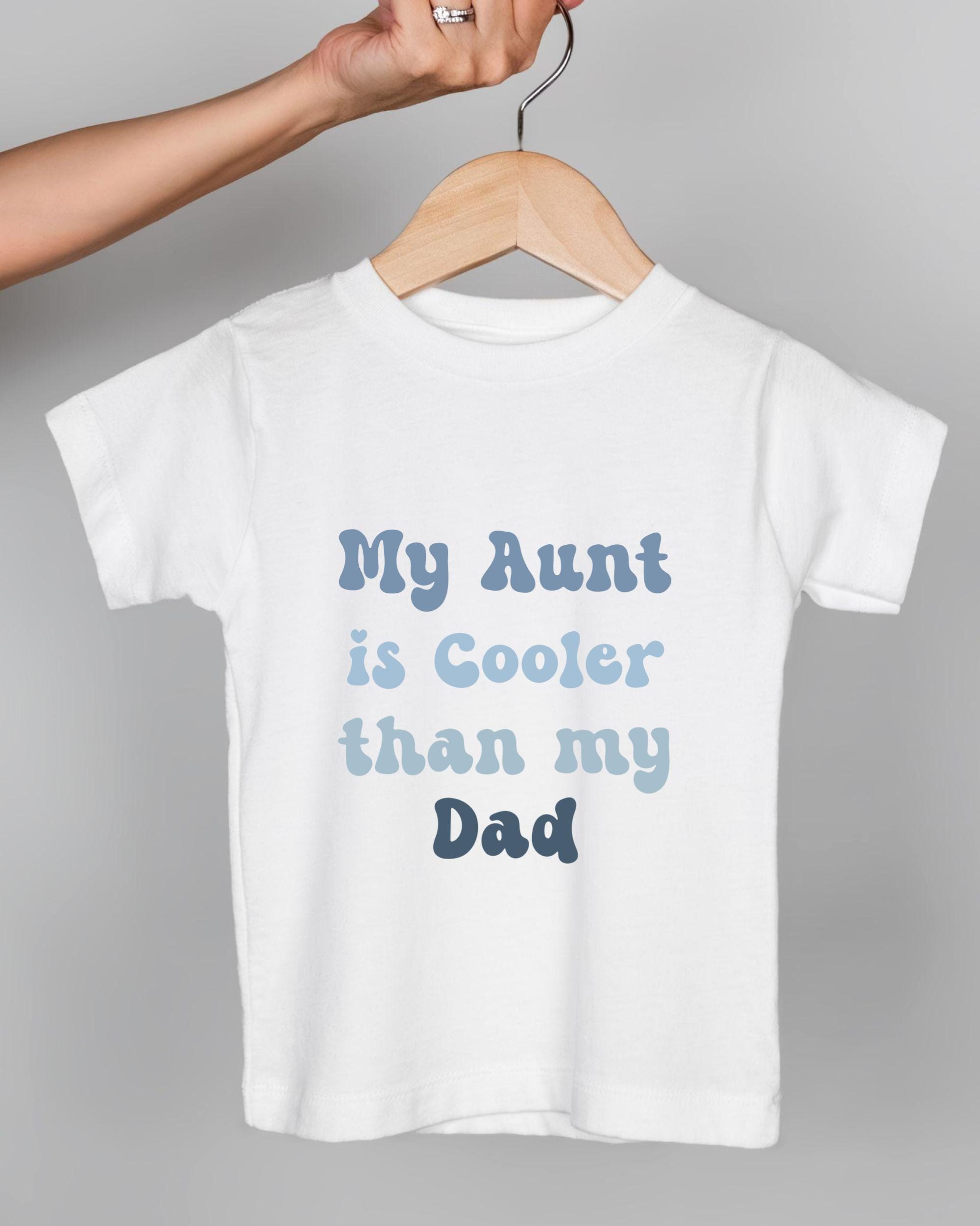 A white t-shirt with text printed on it, hanging on a wooden hanger.