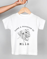 A white t-shirt with a black and white illustration of a dog's face and the text "Loved & Protected by Milo" printed on it.