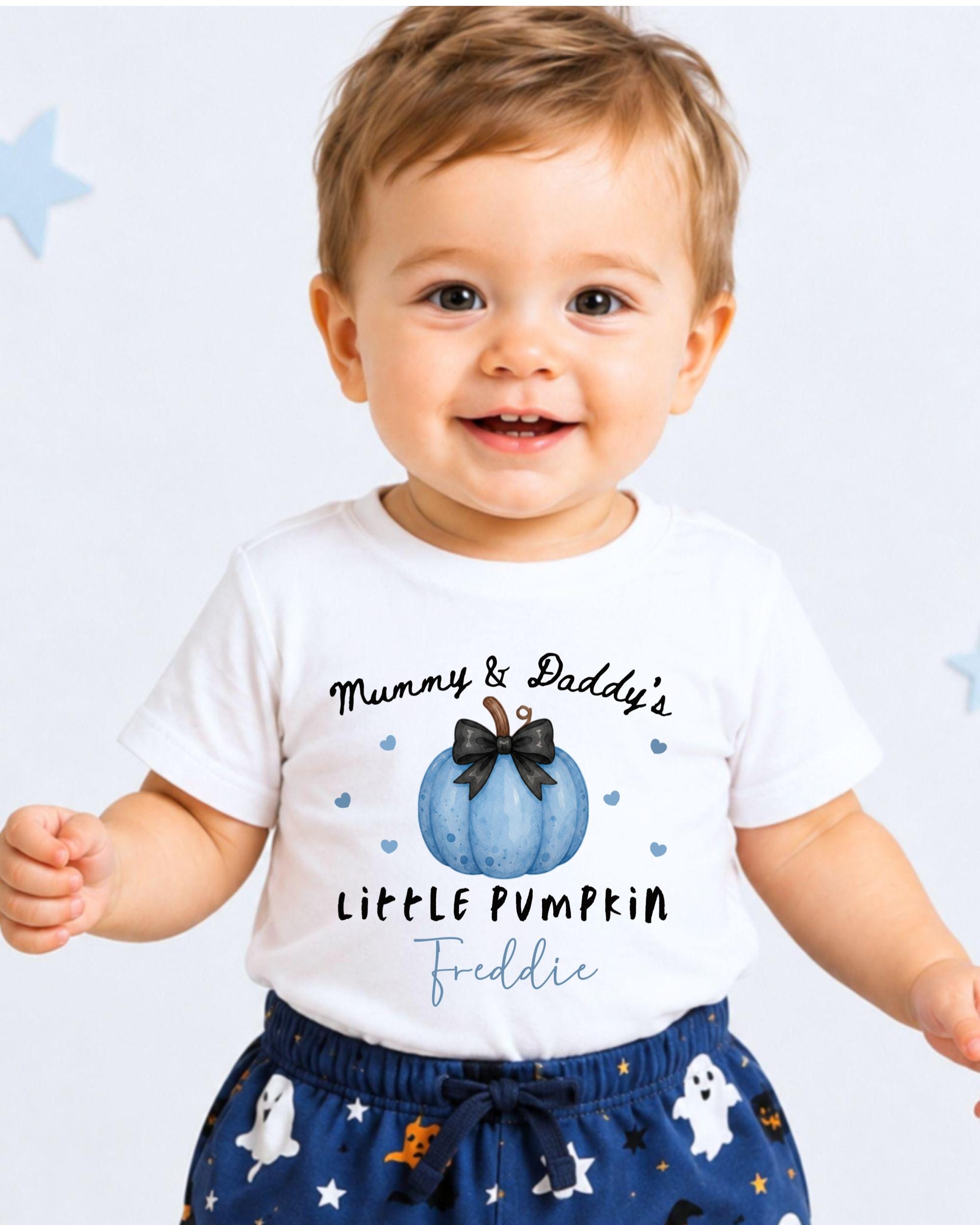 A smiling baby boy wearing a white t-shirt with a pumpkin graphic and text that says "Mummy & Daddy's LITTLE PUMPKIN Feddie".