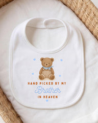 A white bib with a teddy bear and the text "Hand picked by my Brother in Heaven" printed on it.