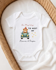 A white onesie with a teddy bear and a car graphic, along with the text "On My Way to Meet My Nana & Papa".