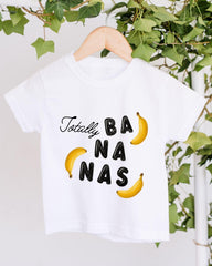 A white t-shirt with the text "Totally BANANA" printed on it, along with two yellow bananas.