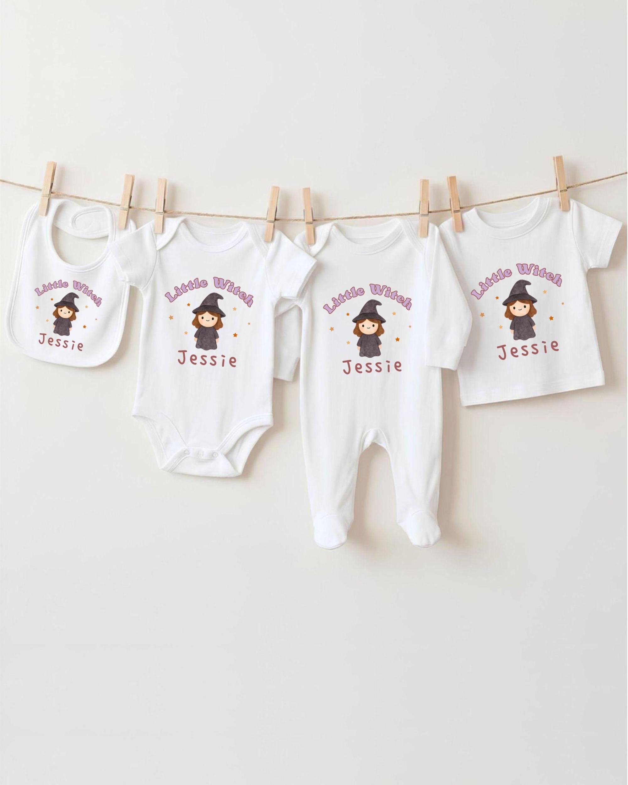 A collection of white baby clothes, including onesies and bibs, with a cartoon character printed on them. The clothes are hanging on a clothesline, and there are four of them in total.