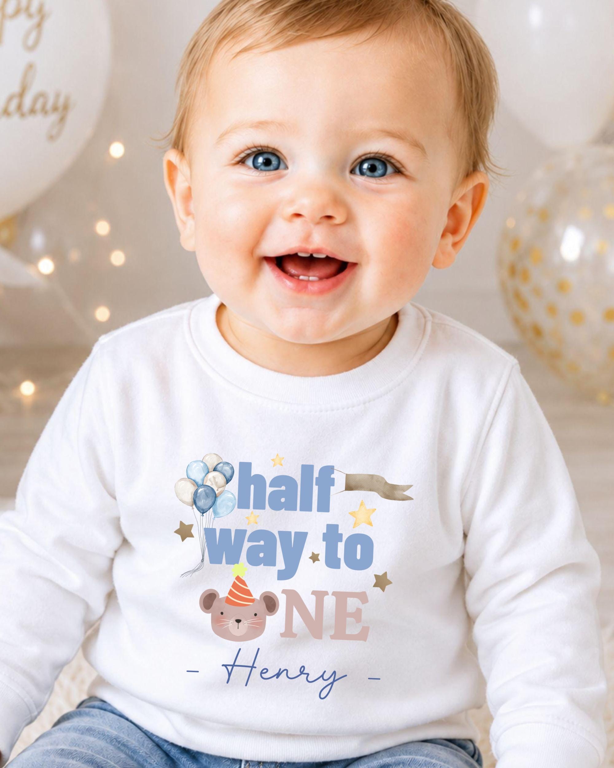 A smiling baby boy wearing a white shirt with a birthday message and a cartoon character.