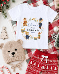 A white t-shirt with a Christmas-themed design, a knitted bear hat, and red patterned shorts, all surrounded by holiday decorations such as a Christmas tree, ornaments, and a snowflake.