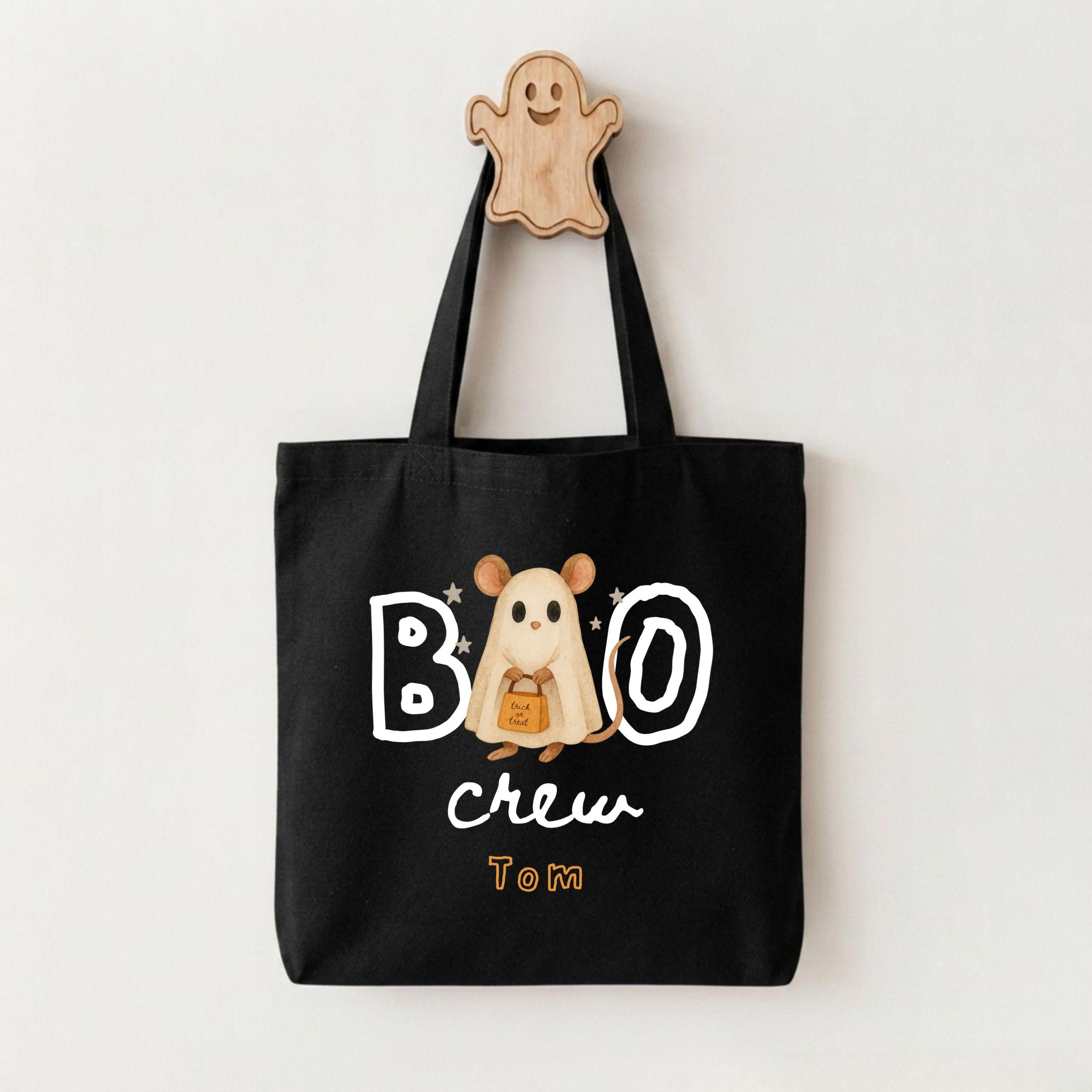 A black tote bag with a Halloween-themed design, including a ghost character and the text "BOO crew Tom".