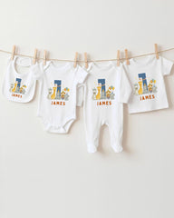A collection of white baby clothes, including onesies and pants, with the name "James" printed on them, hanging on a clothesline.