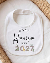 A white baby bib with personalized text and a graphic design.