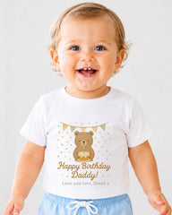 A smiling baby boy wearing a white t-shirt with a birthday message and a bear graphic.