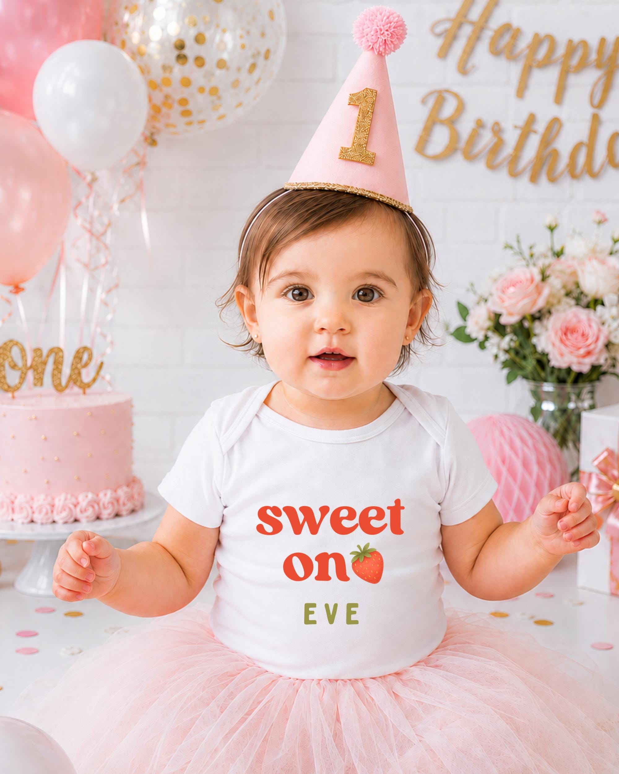 A young girl wearing a birthday hat and a white t-shirt with the text "Sweet on Eve" is posing in front of a birthday cake and balloons.