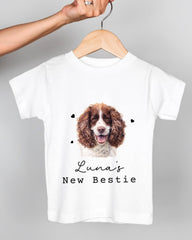 A white t-shirt with a picture of a brown and white dog, along with the text "Luna's New Bestie" printed on it.
