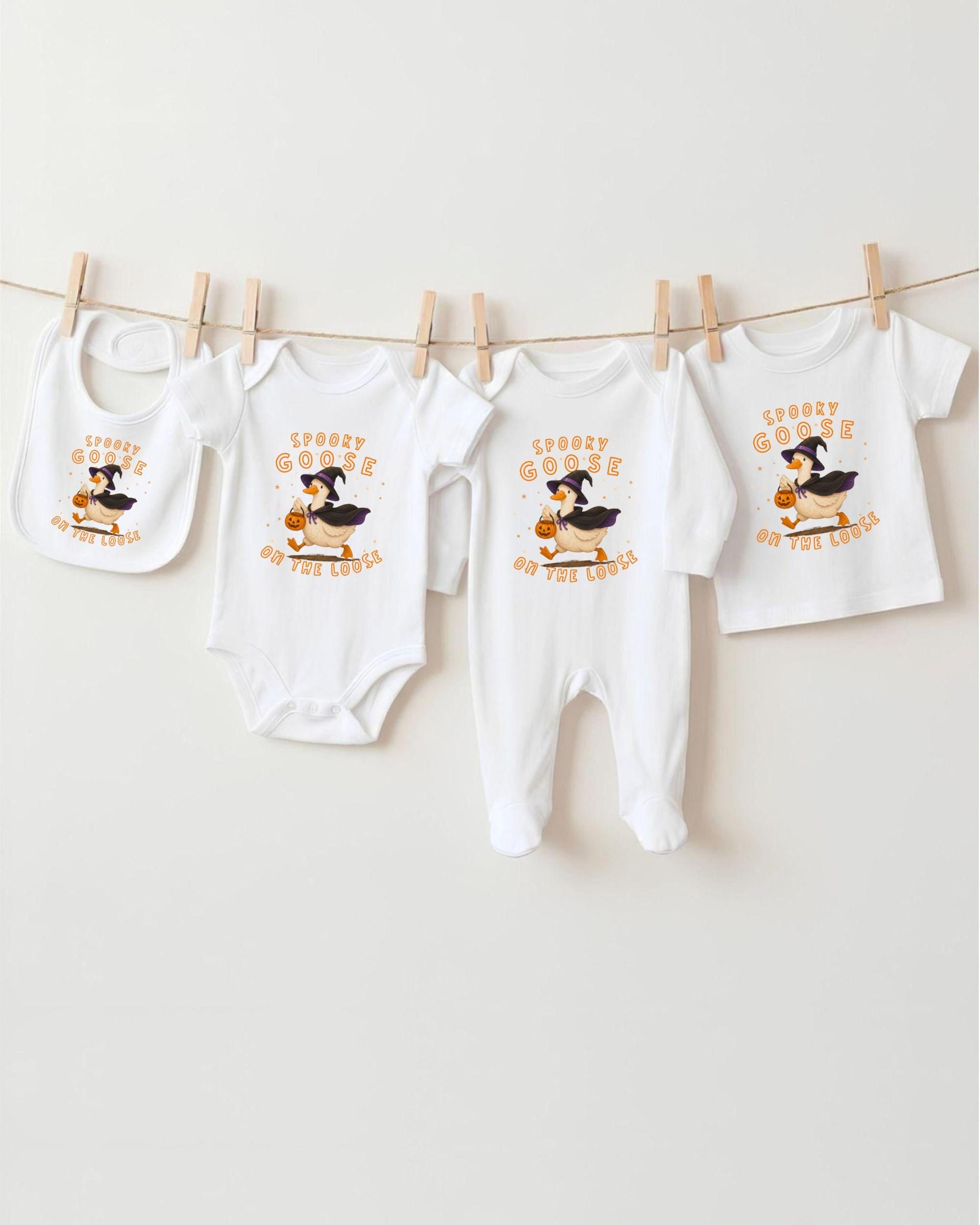 A collection of Halloween-themed baby clothes, including bibs and onesies, hanging on a clothesline.