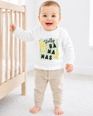 A smiling baby boy wearing a white sweatshirt with a banana graphic and the text "TotALLY BANANA" printed on it.