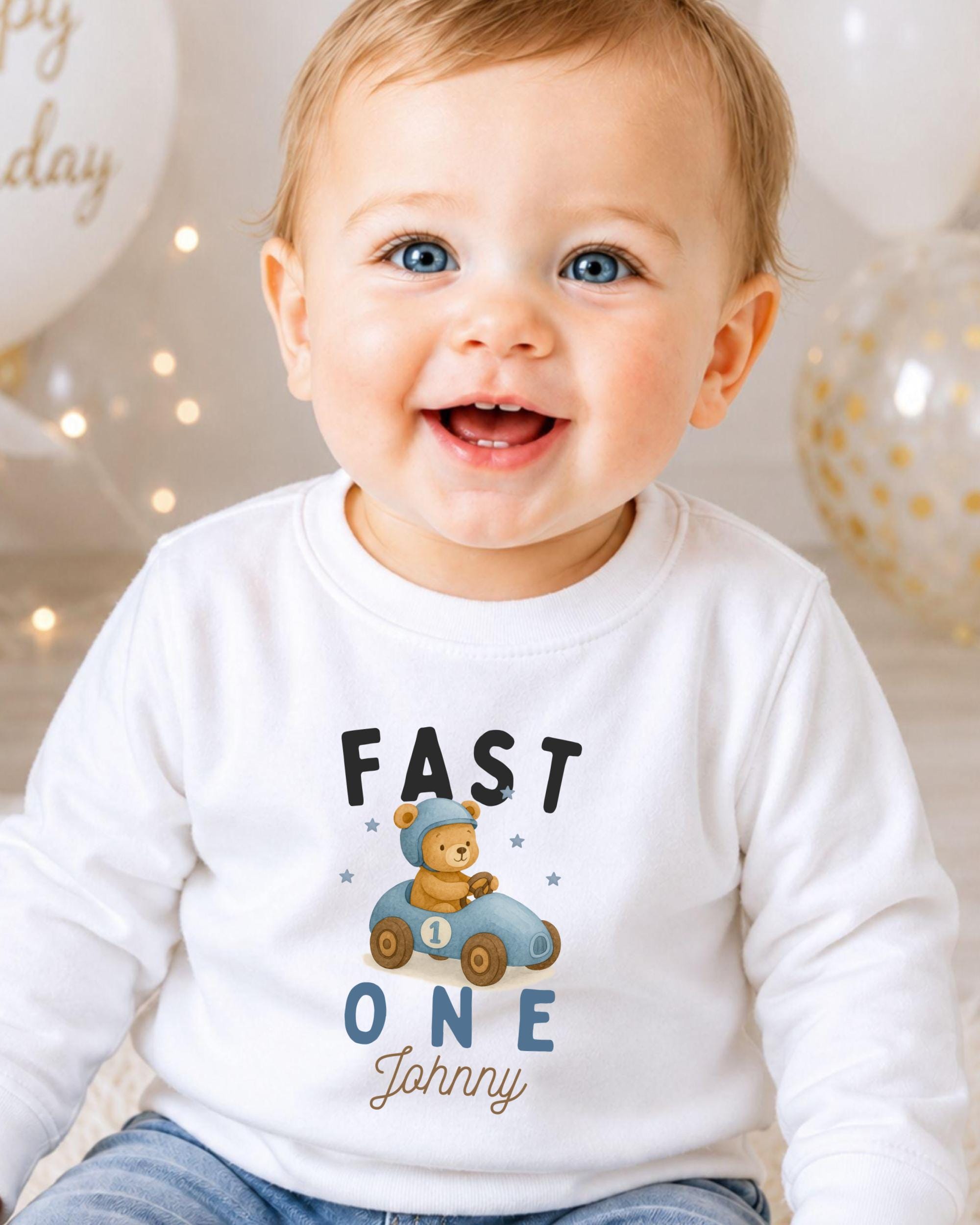 A smiling baby boy wearing a white shirt with a teddy bear and the text "FAST ONE Johnny" printed on it.