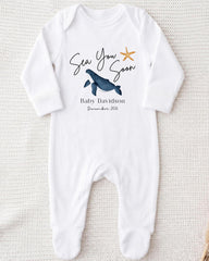 A white onesie with a graphic of a blue whale and a starfish, along with the text "Sea You Soon Baby Davidson December 2016".