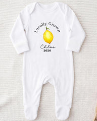 A white onesie with a printed design of a lemon and the text "Locally Grown Chloe 2026" printed on it.