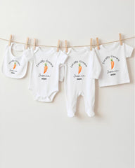 A row of white baby clothes with the text "Locally Grown" printed on them, along with an image of a carrot.
