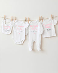 a collection of baby clothes, including bibs and onesies, hanging on a clothesline.