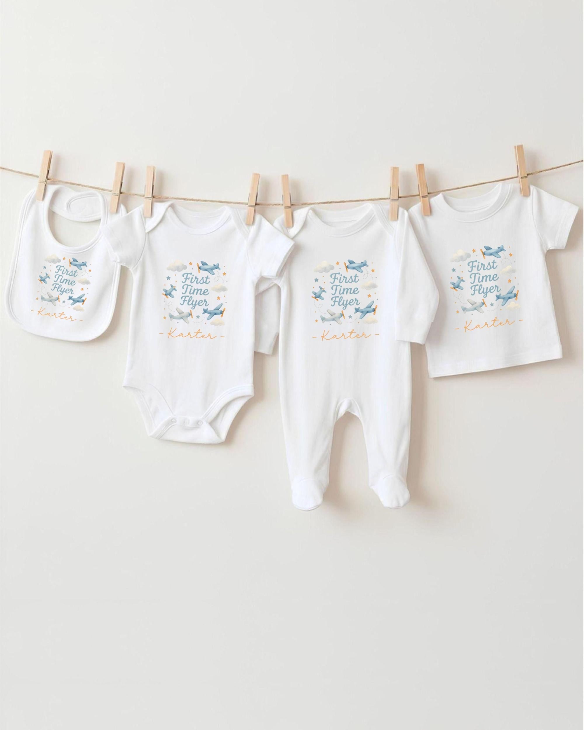 A row of four white baby clothes, including bibs and onesies, hanging on a clothesline.