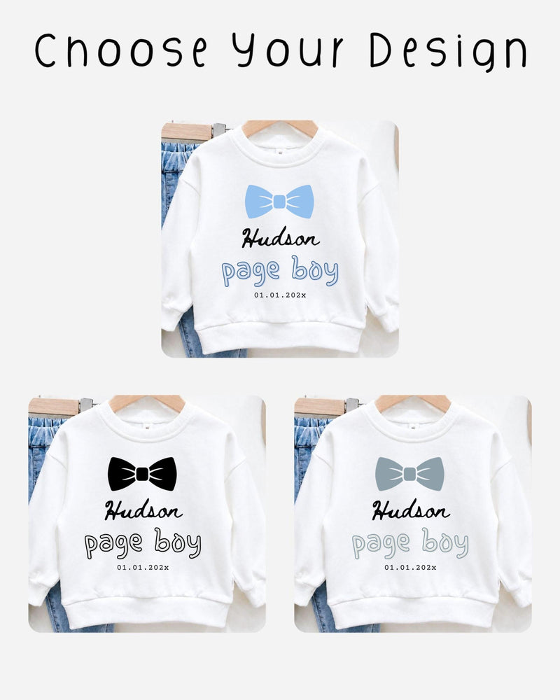 three white sweatshirts with the name "Hudson" and the date "01.01.2023" printed on them. The sweatshirts are arranged on hangers, suggesting they are for sale or display.