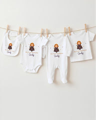 A row of four white baby clothes with a small cartoon character on them, hanging on a clothesline.