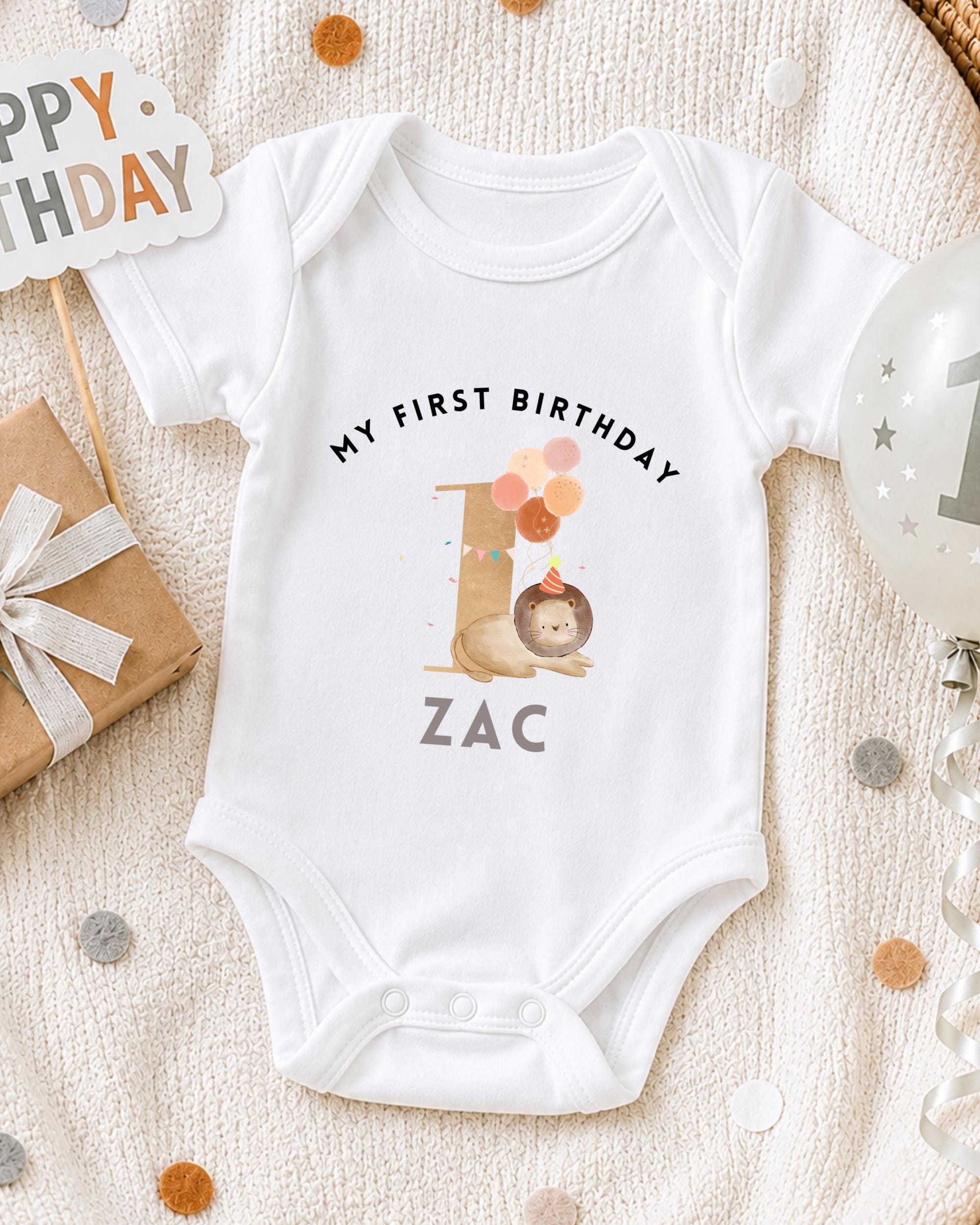 A white onesie with a personalized birthday message for a baby named Zac, along with a "Happy Birthday" sign, a balloon, and confetti.