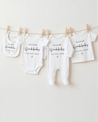 a row of white baby clothes hanging on a clothesline, each with a unique message printed on it.