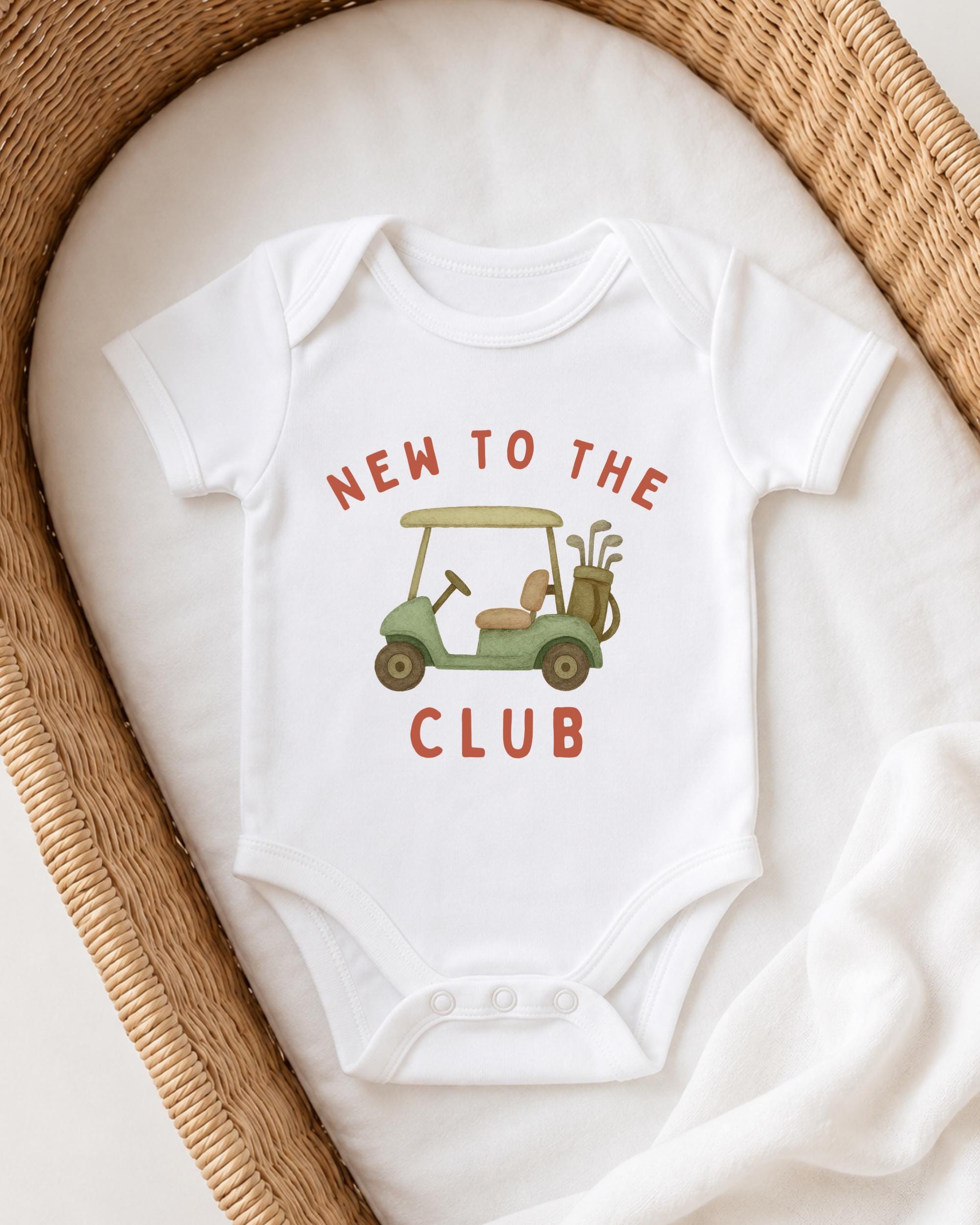 A white baby onesie with a golf cart graphic and the text "NEW TO THE CLUB" printed on it.