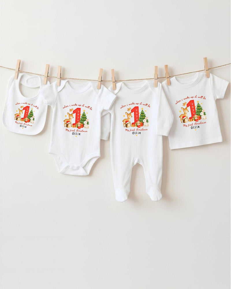 A row of four white baby clothes with personalized Christmas-themed designs hanging on a clothesline.