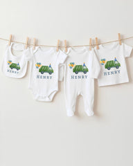 A collection of baby clothes, including onesies and bibs, are hanging on a clothesline.